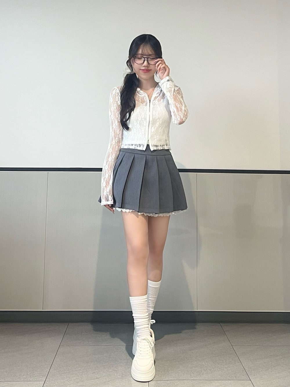 ホワイト系のパーカー、グレー系のスカート、ホワイト系のスニーカーを着用したレディースの夏コーディネートの2枚目の写真