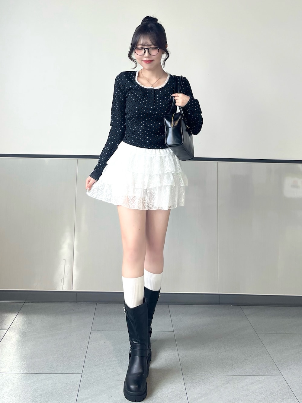 ブラック系のTシャツ/カットソー、ホワイト系のスカート、ブラック系のブーツを着用したレディースの秋コーディネートの2枚目の写真