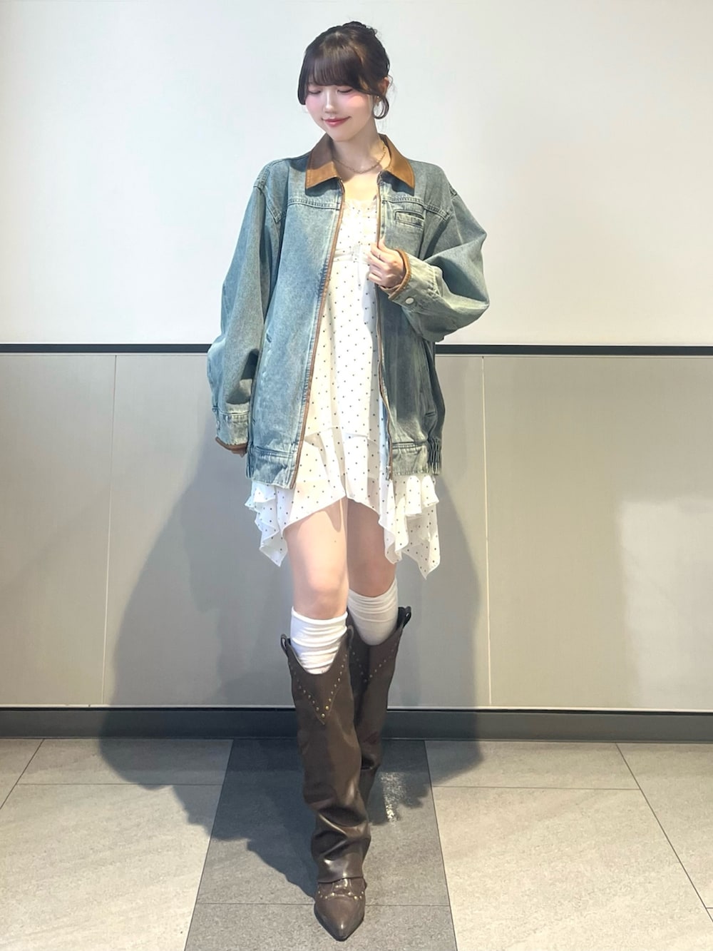 ブルー系のデニムジャケット、ブラウン系のボストンバッグ、ホワイト系のワンピースを着用したレディースの春コーディネートの2枚目の写真