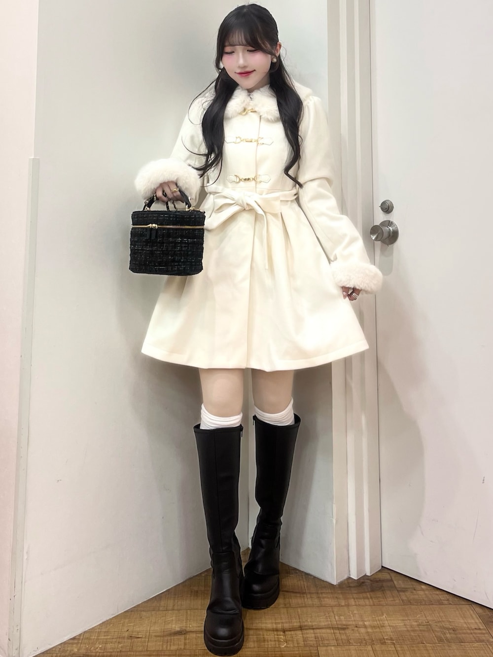 ブラック系のショルダーバッグ、ブラック系のブーツ、ホワイト系のその他アウターを着用したレディースの冬コーディネートの2枚目の写真