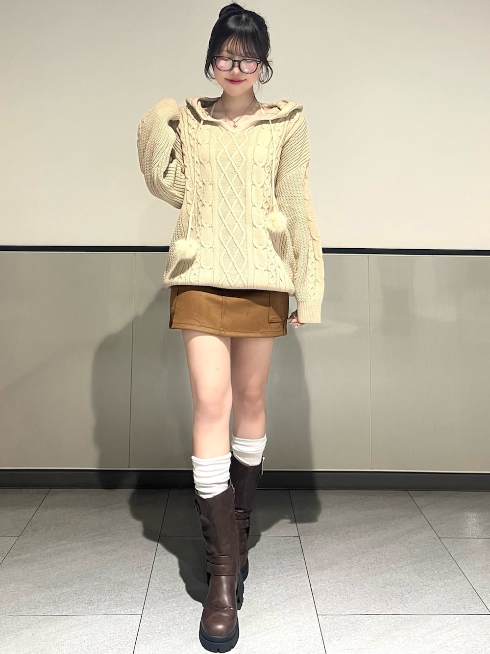 ベージュ系のパーカー、イエロー系のスカート、ブラウン系のブーツを着用したレディースの冬コーディネートの2枚目の写真