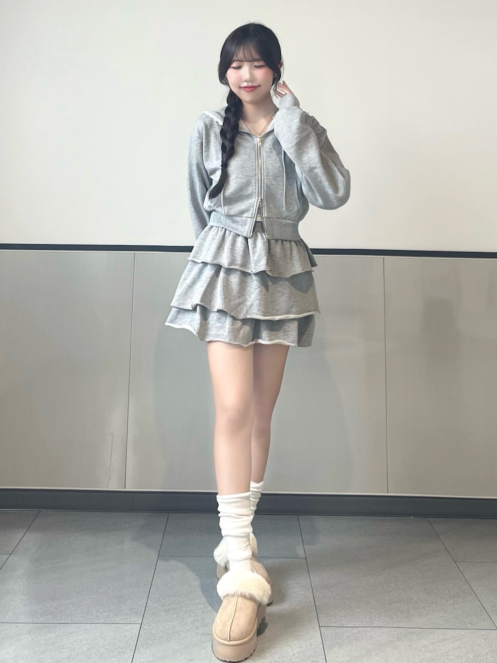 グレー系のパーカー、グレー系のスカート、ベージュ系のブーツを着用したレディースの秋コーディネートの2枚目の写真