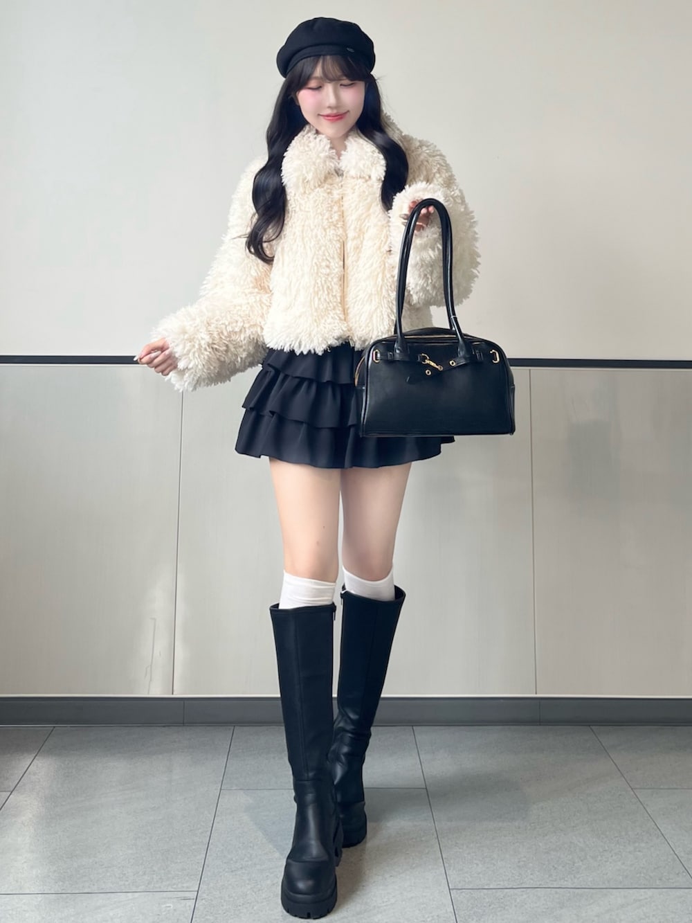 ホワイト系のブルゾン、ブラック系のスカート、ブラック系のブーツを着用したレディースの秋コーディネートの2枚目の写真