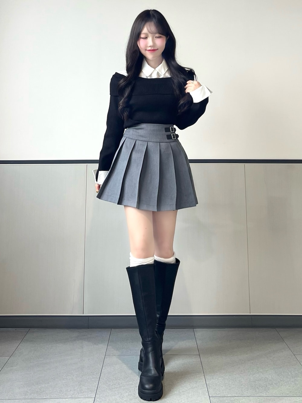 ブラック系のニット/セーター、グレー系のスカート、ブラック系のブーツを着用したレディースの秋コーディネートの2枚目の写真