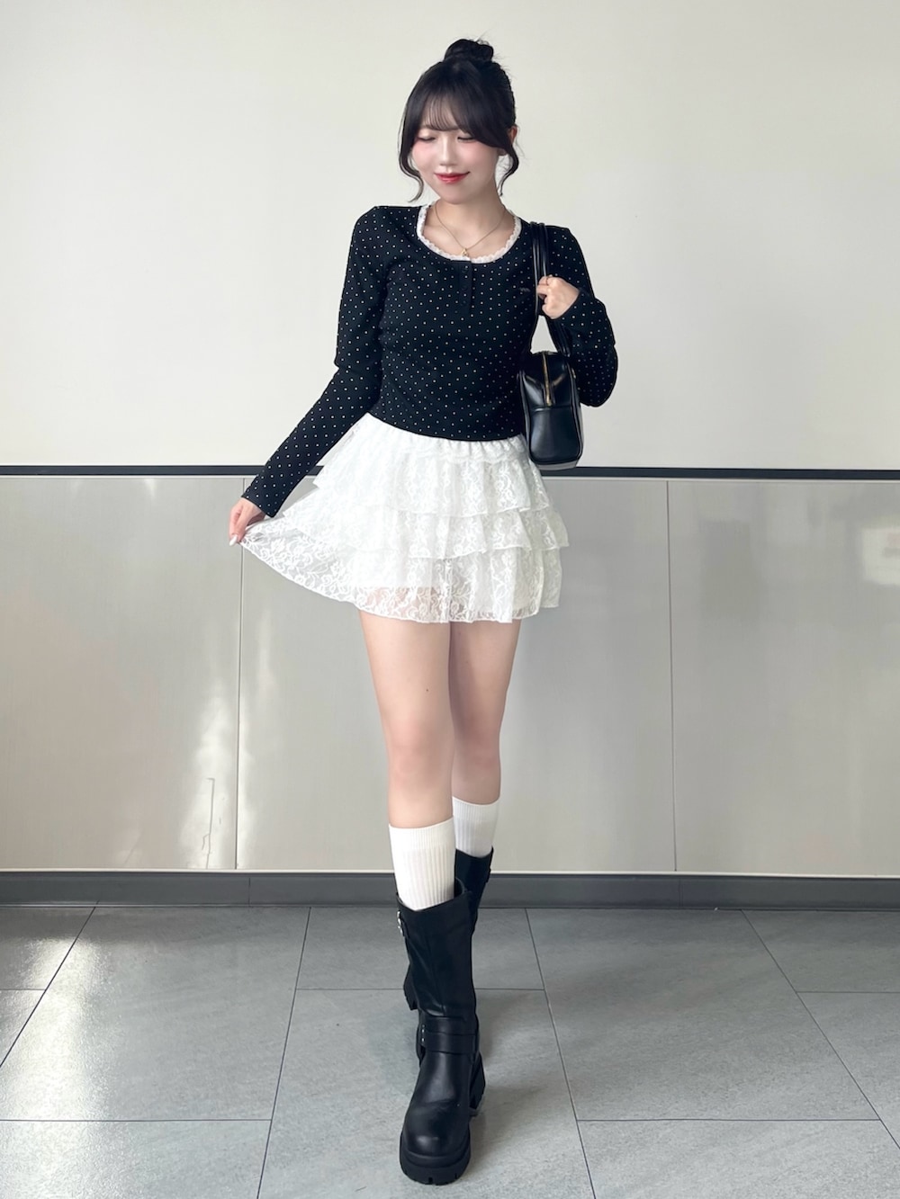 ブラック系のTシャツ/カットソー、ホワイト系のスカート、ブラック系のブーツを着用したレディースの秋コーディネートの3枚目の写真