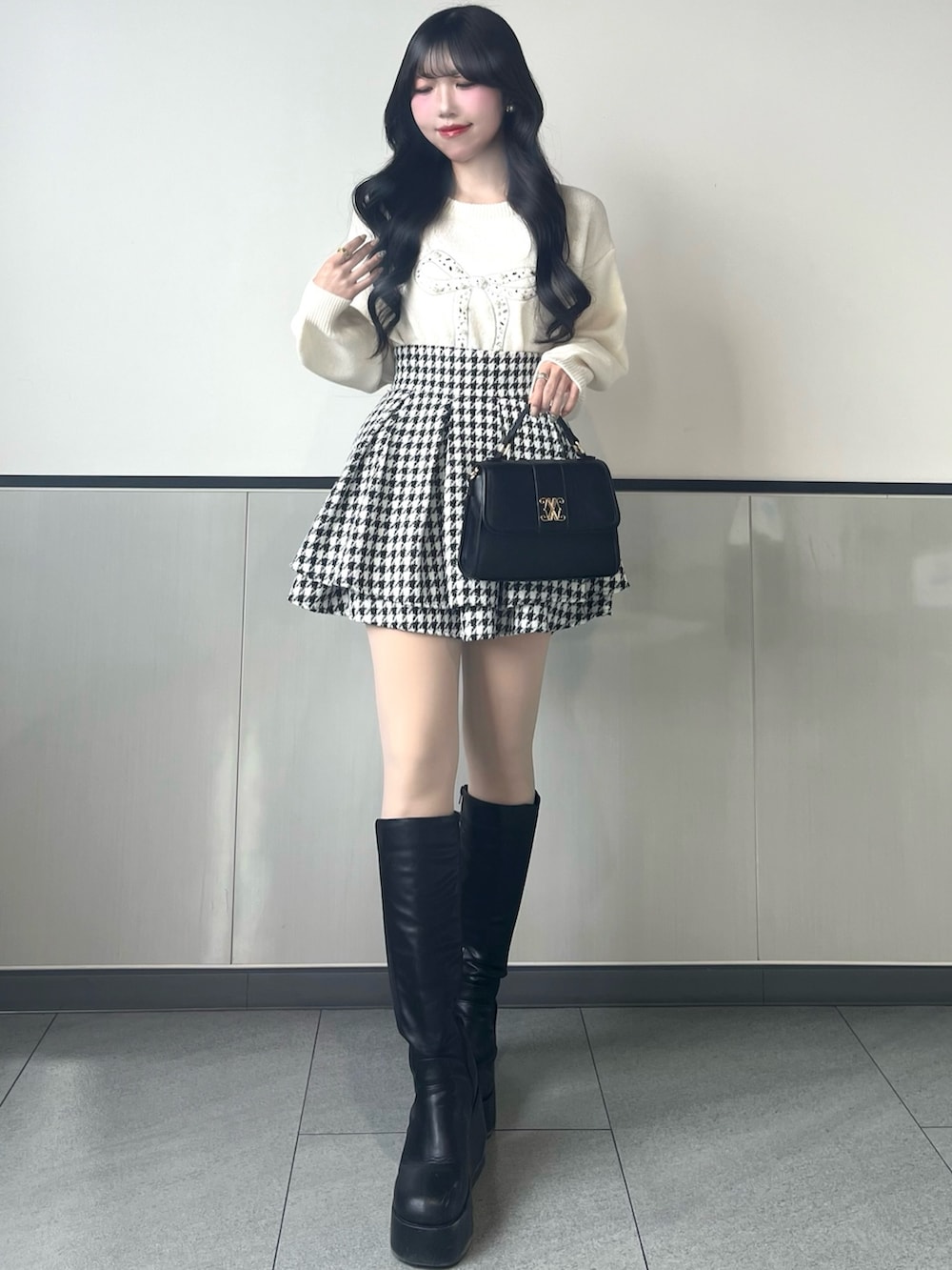 ホワイト系のニット/セーター、その他のスカート、ブラック系のハンドバッグを着用したレディースの冬コーディネートの2枚目の写真