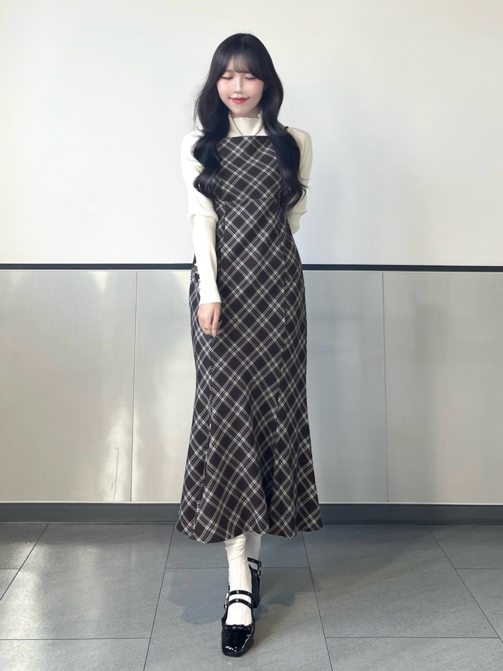 ホワイト系のニット/セーター、ブラウン系のワンピース、ブラック系のパンプスを着用したレディースの秋コーディネートの2枚目の写真