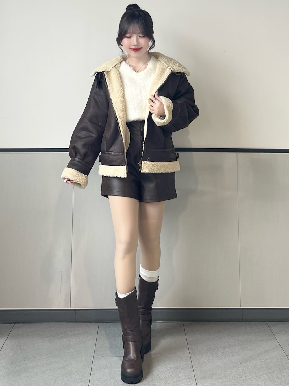 ブラウン系のブルゾン、ホワイト系のニット/セーター、ブラウン系のその他パンツを着用したレディースの秋コーディネートの2枚目の写真