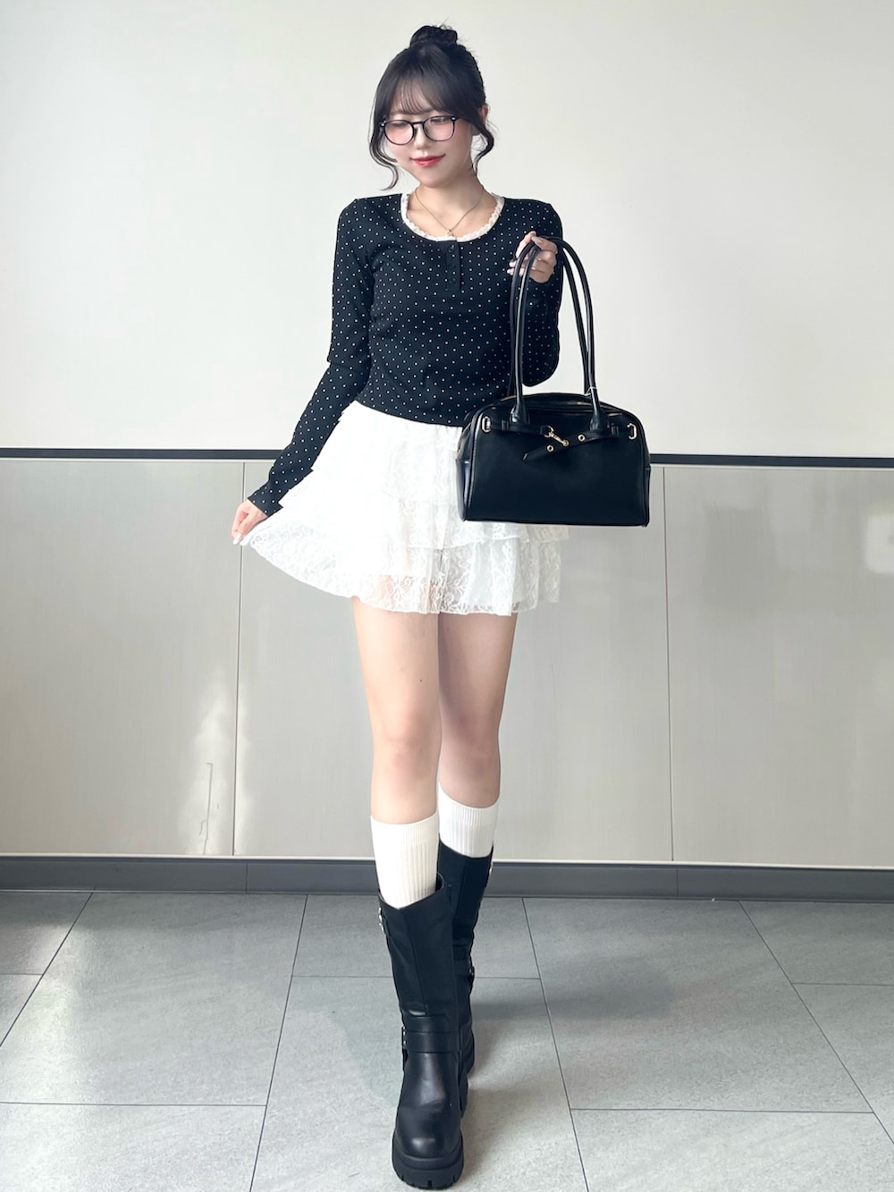 ブラック系のTシャツ/カットソー、ホワイト系のスカート、ブラック系のブーツを着用したレディースの秋コーディネートの4枚目の写真