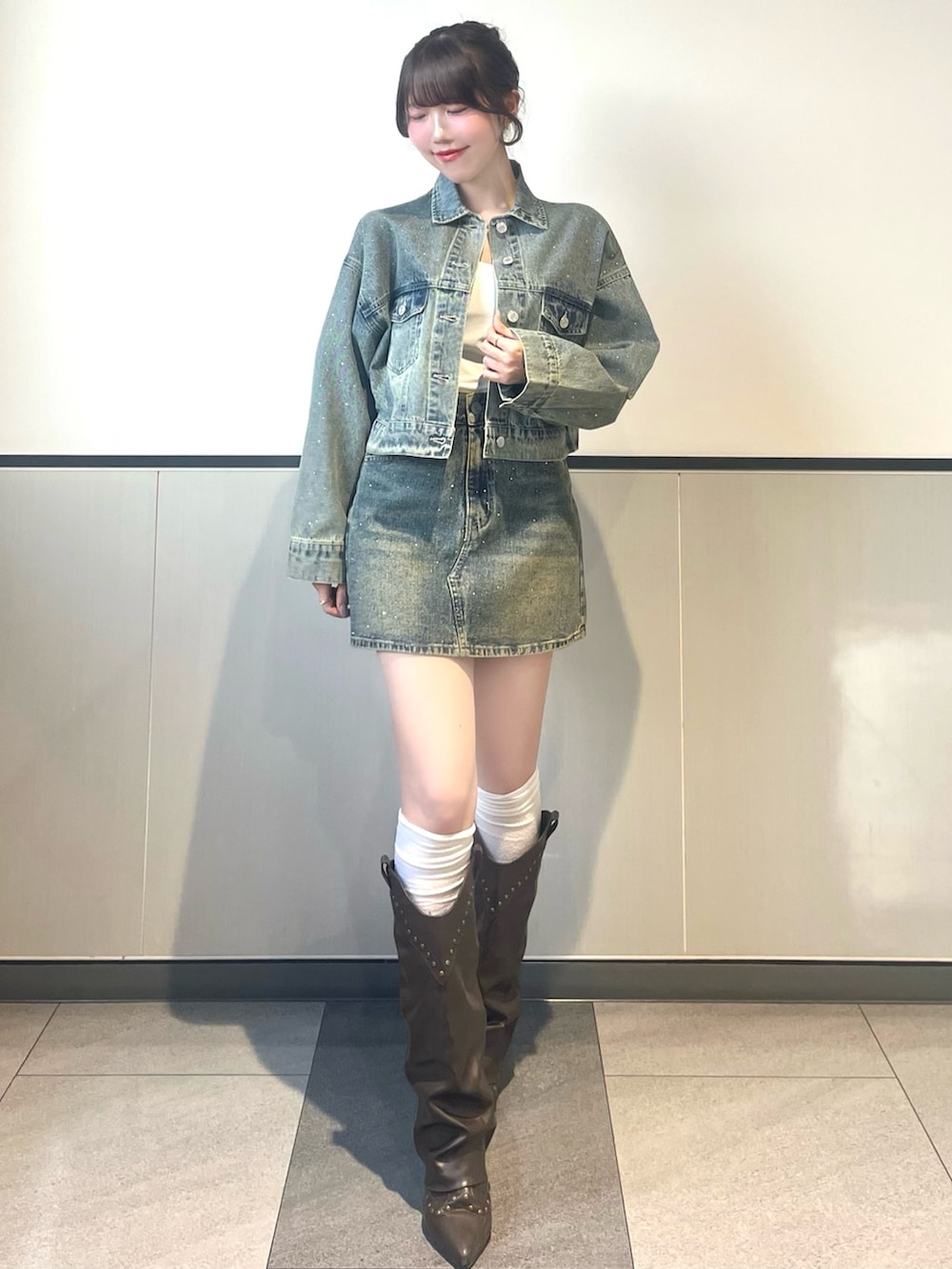 ブルー系のデニムジャケット、ブルー系のデニムスカート、ホワイト系のキャミソールを着用したレディースの春コーディネートの2枚目の写真