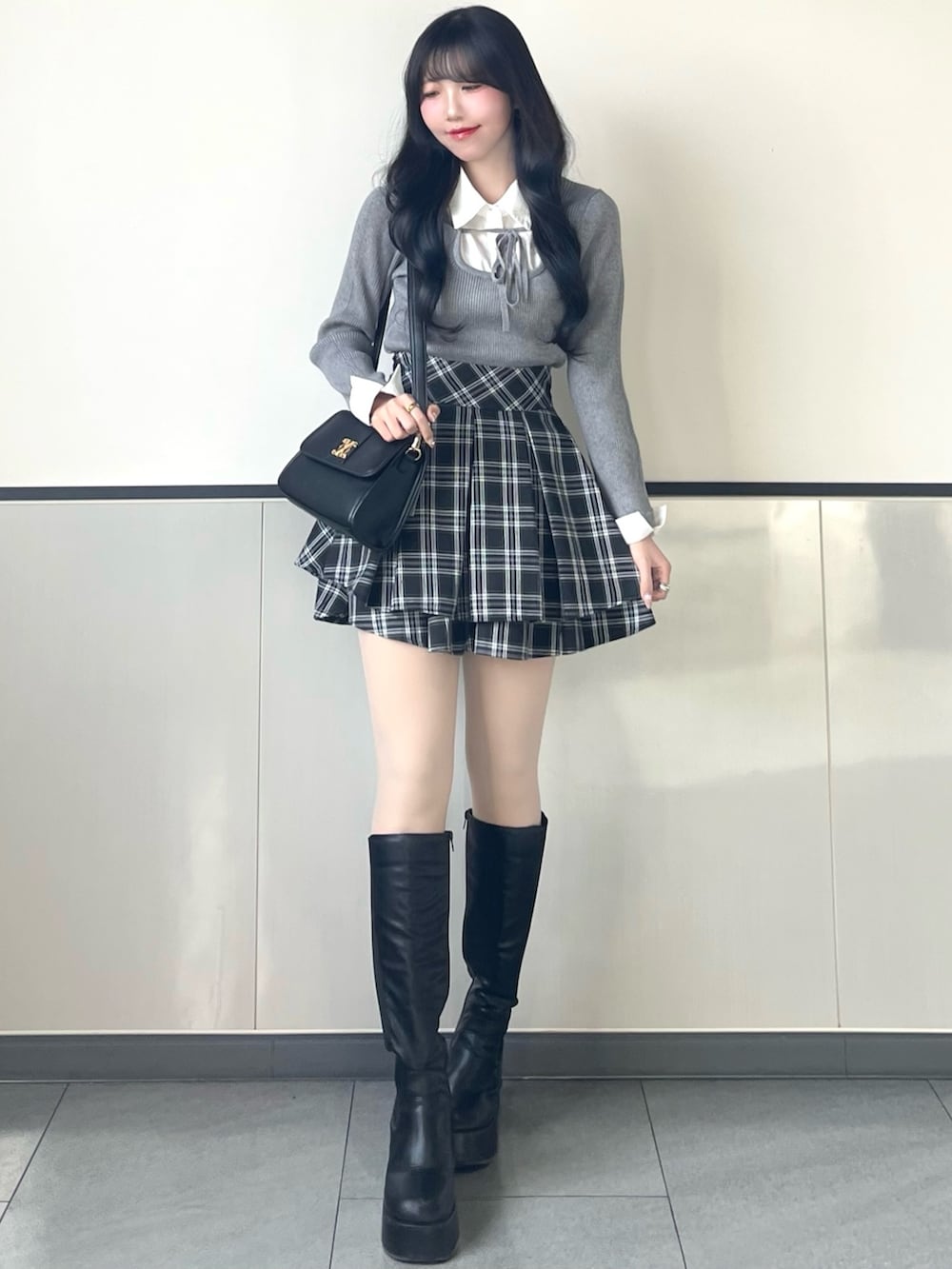 グレー系のニット/セーター、ブラック系のスカート、ブラック系のハンドバッグを着用したレディースの冬コーディネートの2枚目の写真