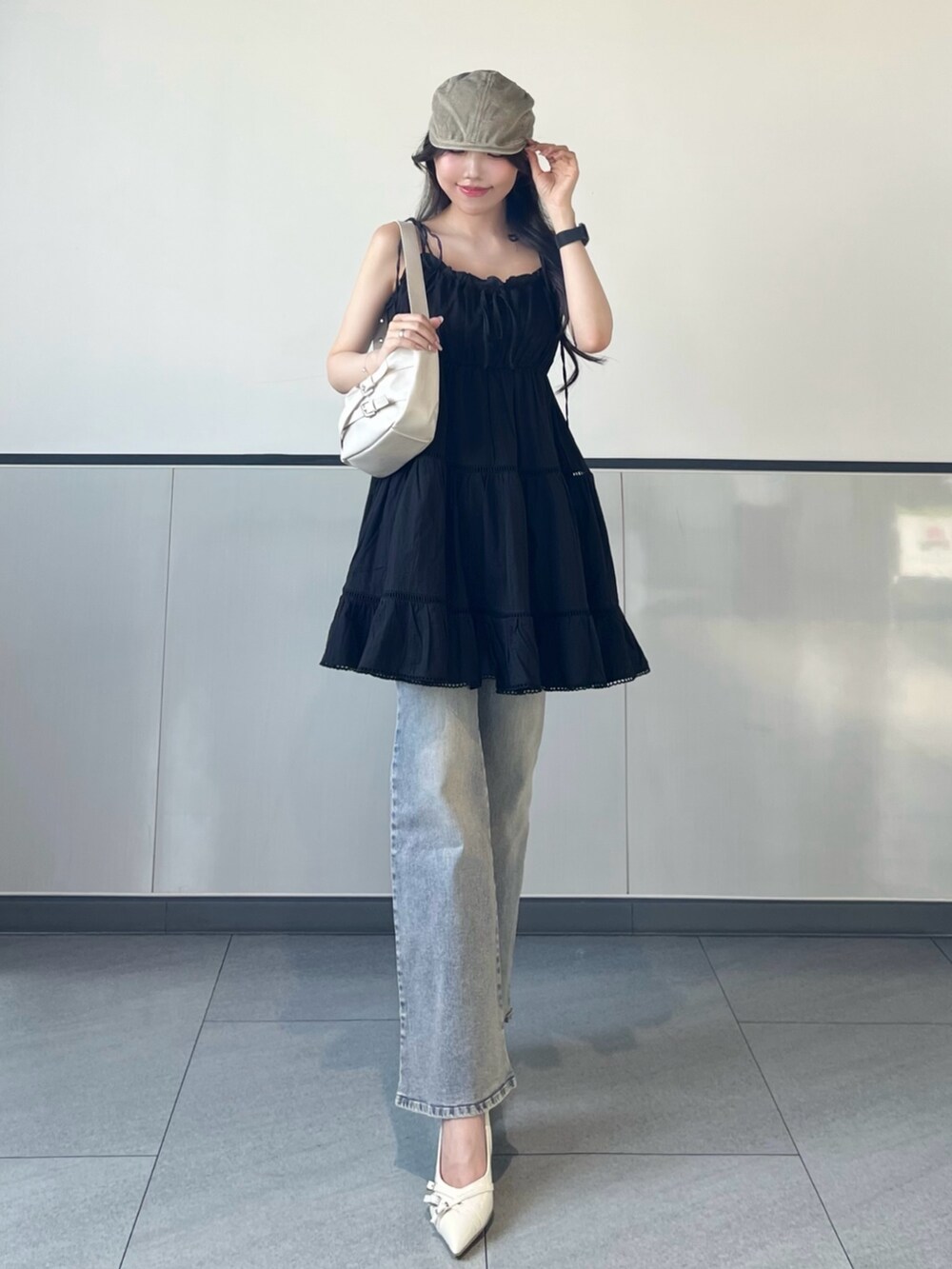 ブラック系のワンピース、ブルー系のデニムパンツ、ホワイト系のパンプスを着用したレディースの夏コーディネートの2枚目の写真