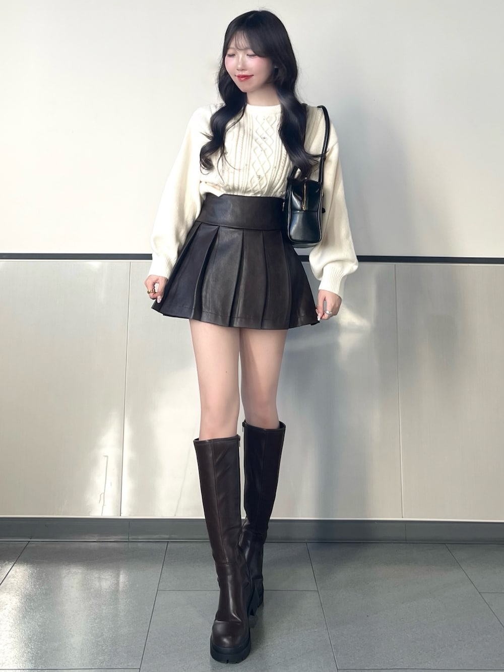 ホワイト系のニット/セーター、ブラウン系のスカート、ブラウン系のブーツを着用したレディースの秋コーディネートの2枚目の写真