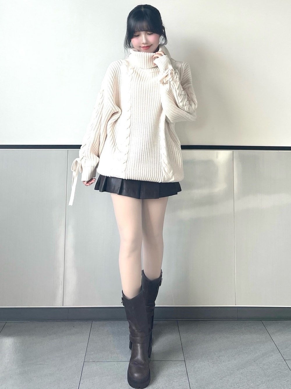 ホワイト系のチュニック、ブラウン系のスカート、ブラウン系のブーツを着用したレディースの冬コーディネートの3枚目の写真