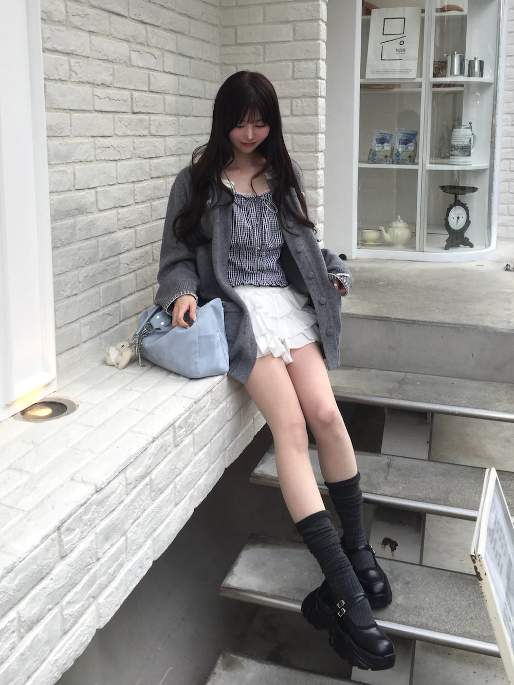 グレー系のカーディガン/ボレロ、ブルー系のトップス、ホワイト系のパンツを着用したレディースの春コーディネートの2枚目の写真