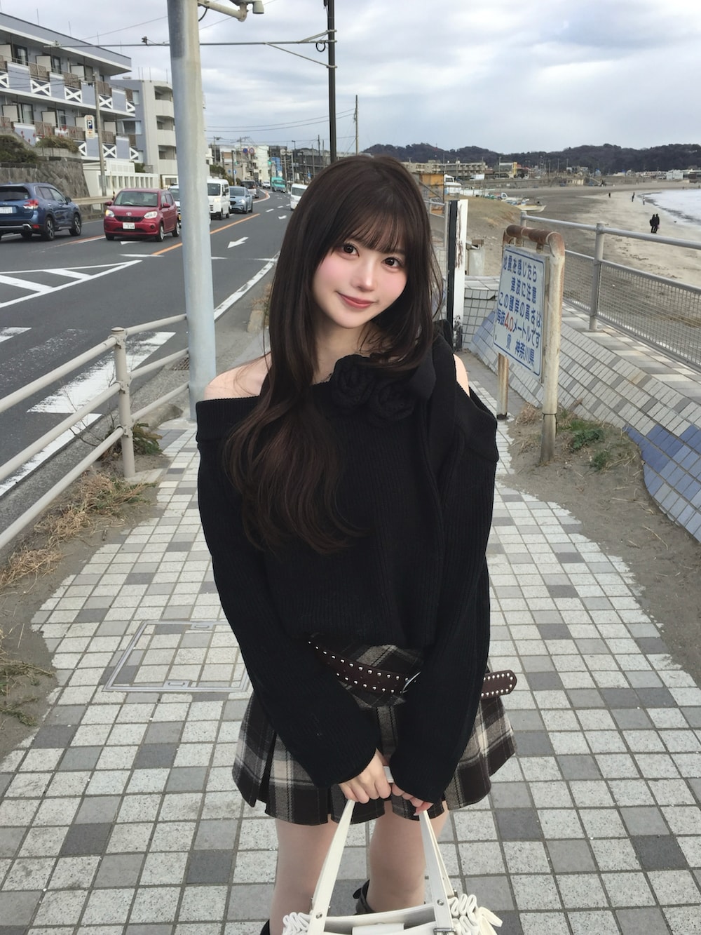 ブラック系のニット/セーター、ブラウン系のスカート、ホワイト系のショルダーバッグを着用したレディースの冬コーディネートの2枚目の写真