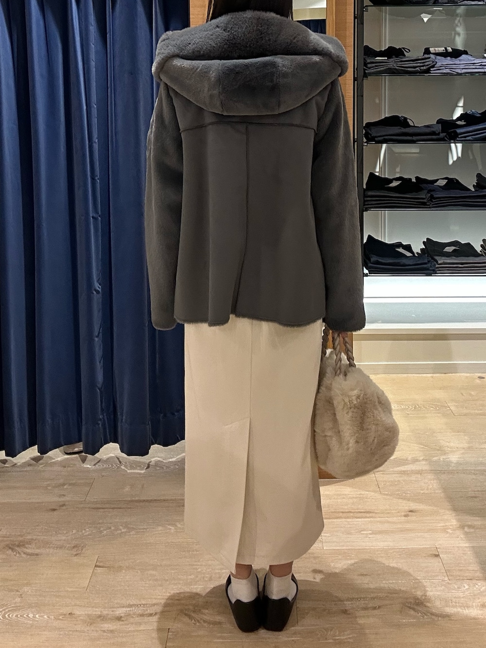 ブルー系のニット/セーター、グレー系のムートンコート、ホワイト系のトートバッグを着用したレディースの冬コーディネートの3枚目の写真