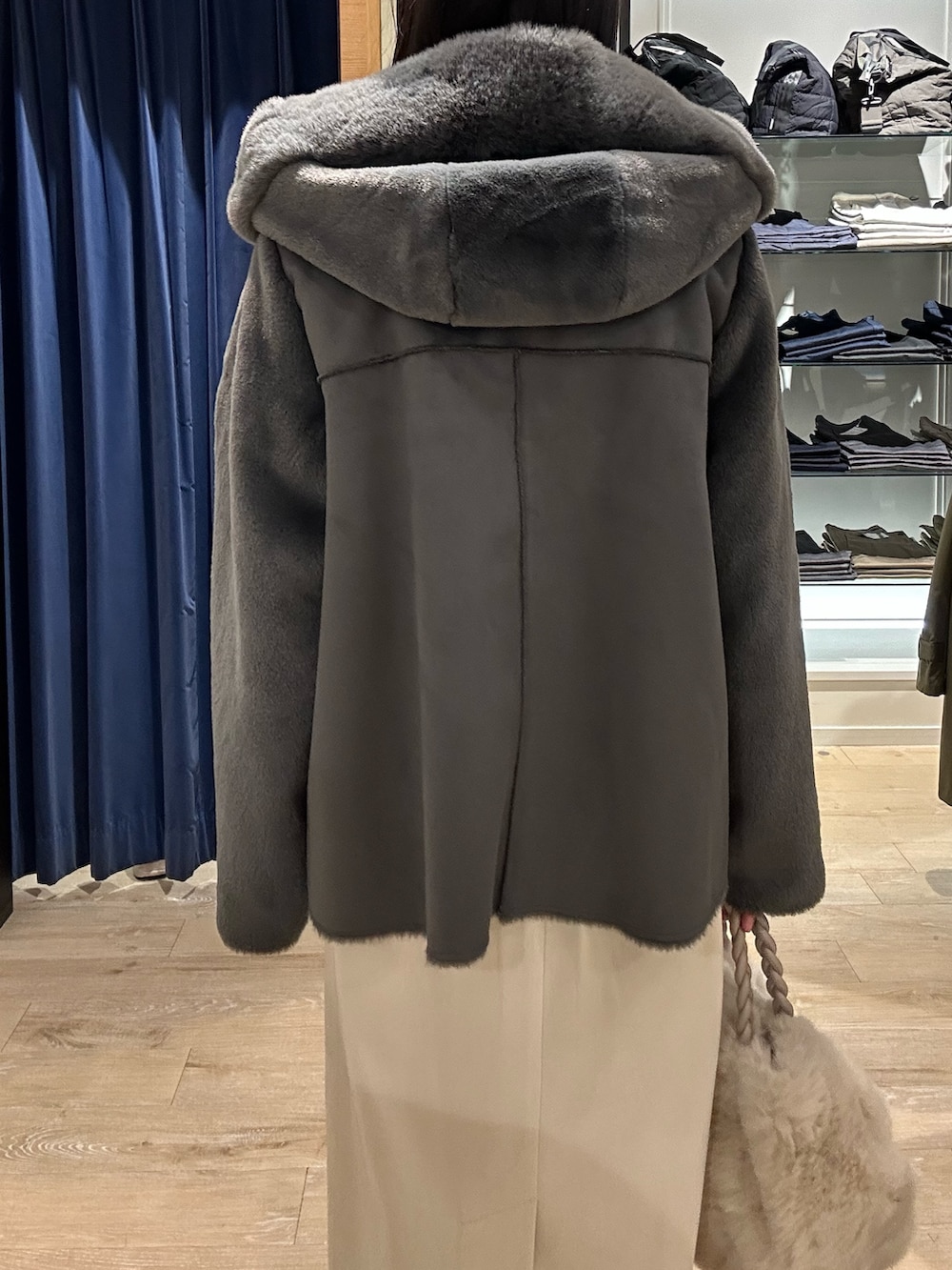 ブルー系のニット/セーター、グレー系のムートンコート、ホワイト系のトートバッグを着用したレディースの冬コーディネートの7枚目の写真