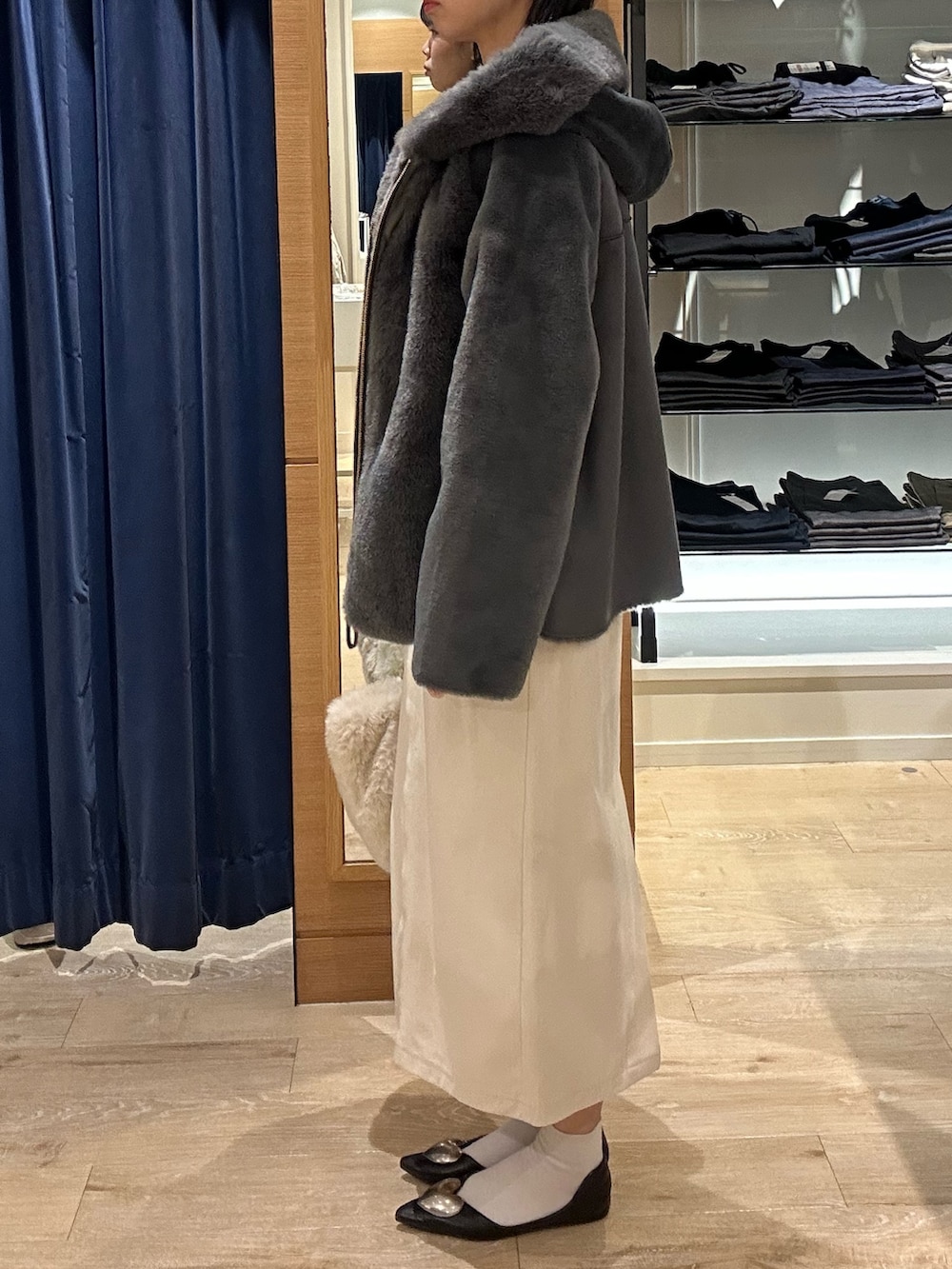 ブルー系のニット/セーター、グレー系のムートンコート、ホワイト系のトートバッグを着用したレディースの冬コーディネートの4枚目の写真