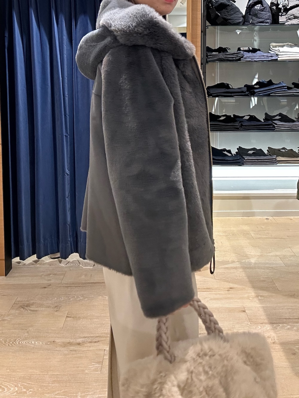 ブルー系のニット/セーター、グレー系のムートンコート、ホワイト系のトートバッグを着用したレディースの冬コーディネートの6枚目の写真