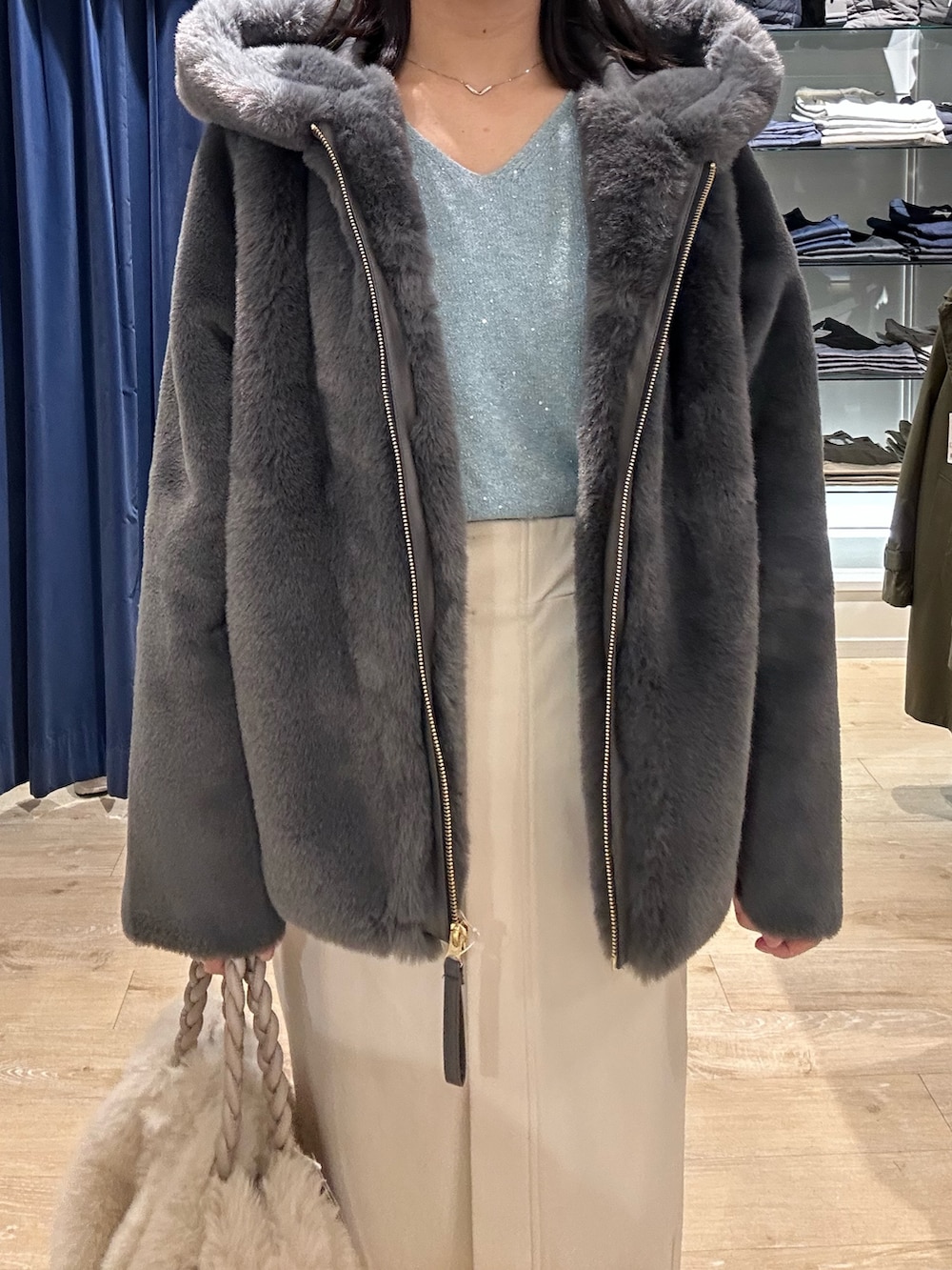 ブルー系のニット/セーター、グレー系のムートンコート、ホワイト系のトートバッグを着用したレディースの冬コーディネートの5枚目の写真