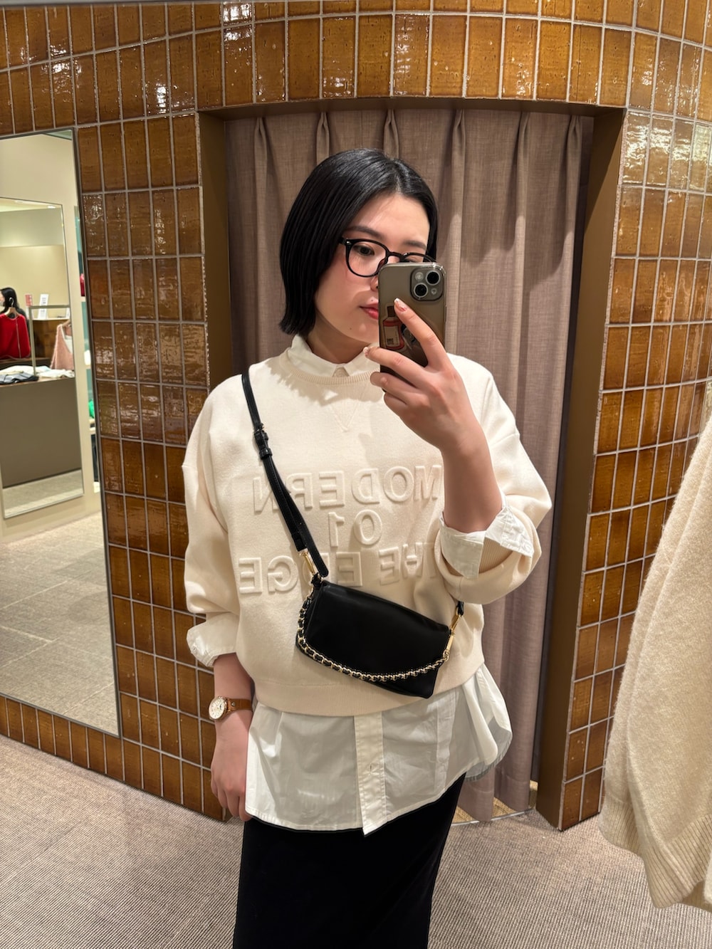 ホワイト系のニット/セーター、ホワイト系のシャツ/ブラウス、ブラック系のスカートを着用したレディースの冬コーディネートの2枚目の写真