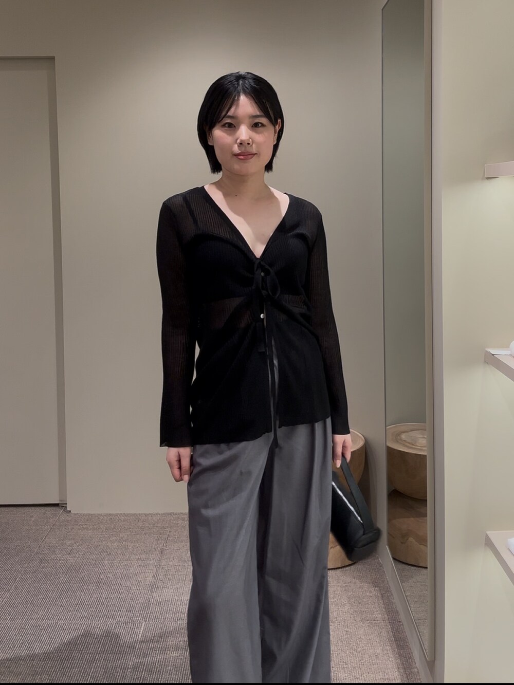 ブラック系のカーディガン/ボレロ、グレー系のスラックスを着用したレディースの夏コーディネートの2枚目の写真