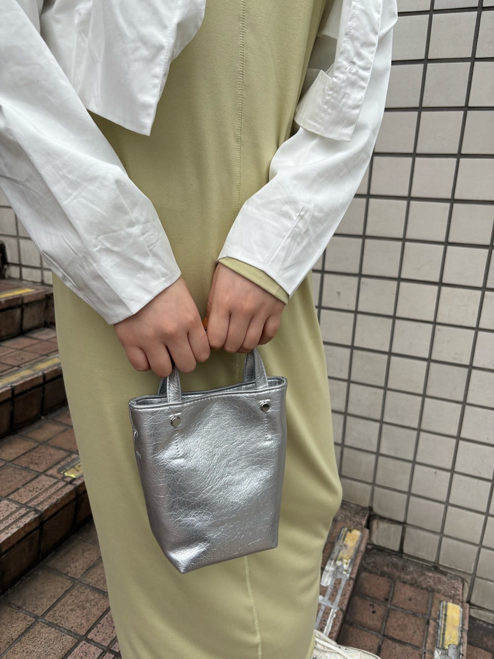 ホワイト系のブルゾン、グリーン系のワンピース、シルバー系のトートバッグを着用したレディースの春コーディネートの2枚目の写真