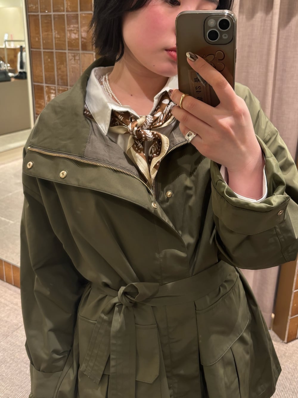 グリーン系のミリタリージャケット、ホワイト系のスカート、イエロー系のその他シューズを着用したレディースの冬コーディネートの2枚目の写真