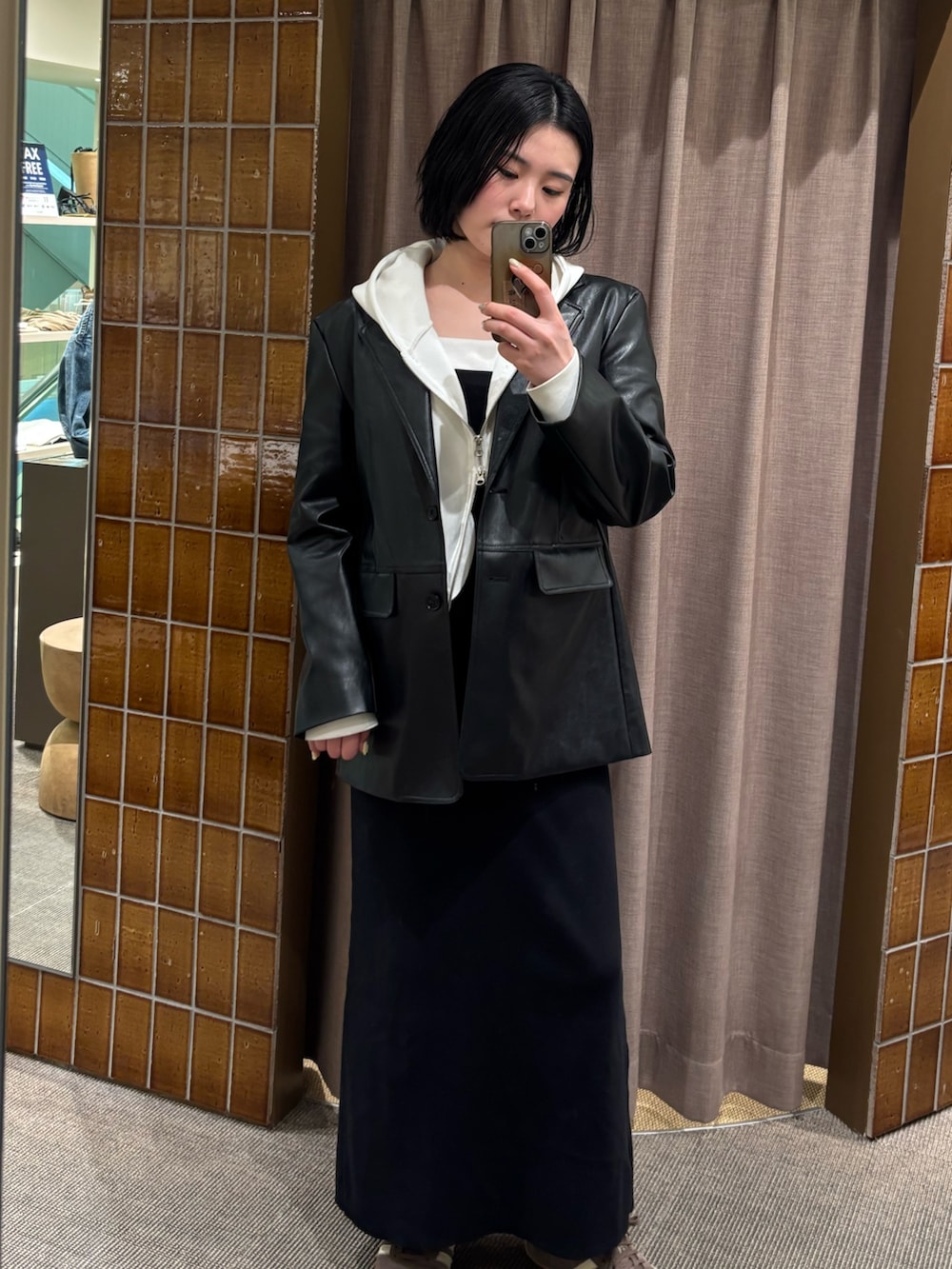 ブラック系のテーラードジャケット、ホワイト系のパーカー、ブラック系のワンピースを着用したレディースの春コーディネートの2枚目の写真