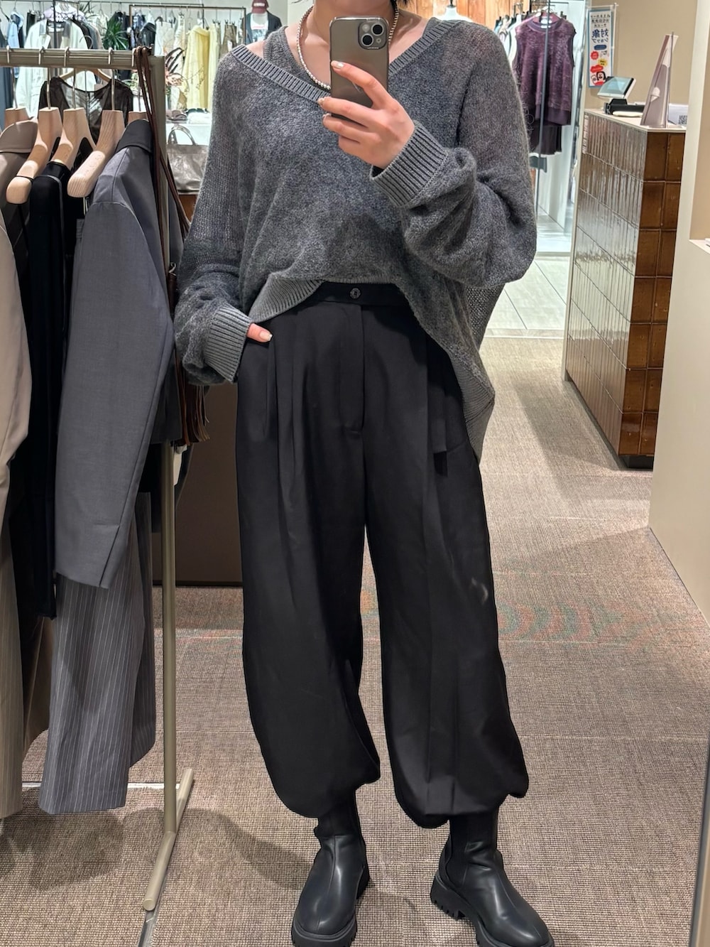 グレー系のニット/セーター、ブラック系のその他パンツ、ブラック系のブーツを着用したレディースの秋コーディネートの3枚目の写真