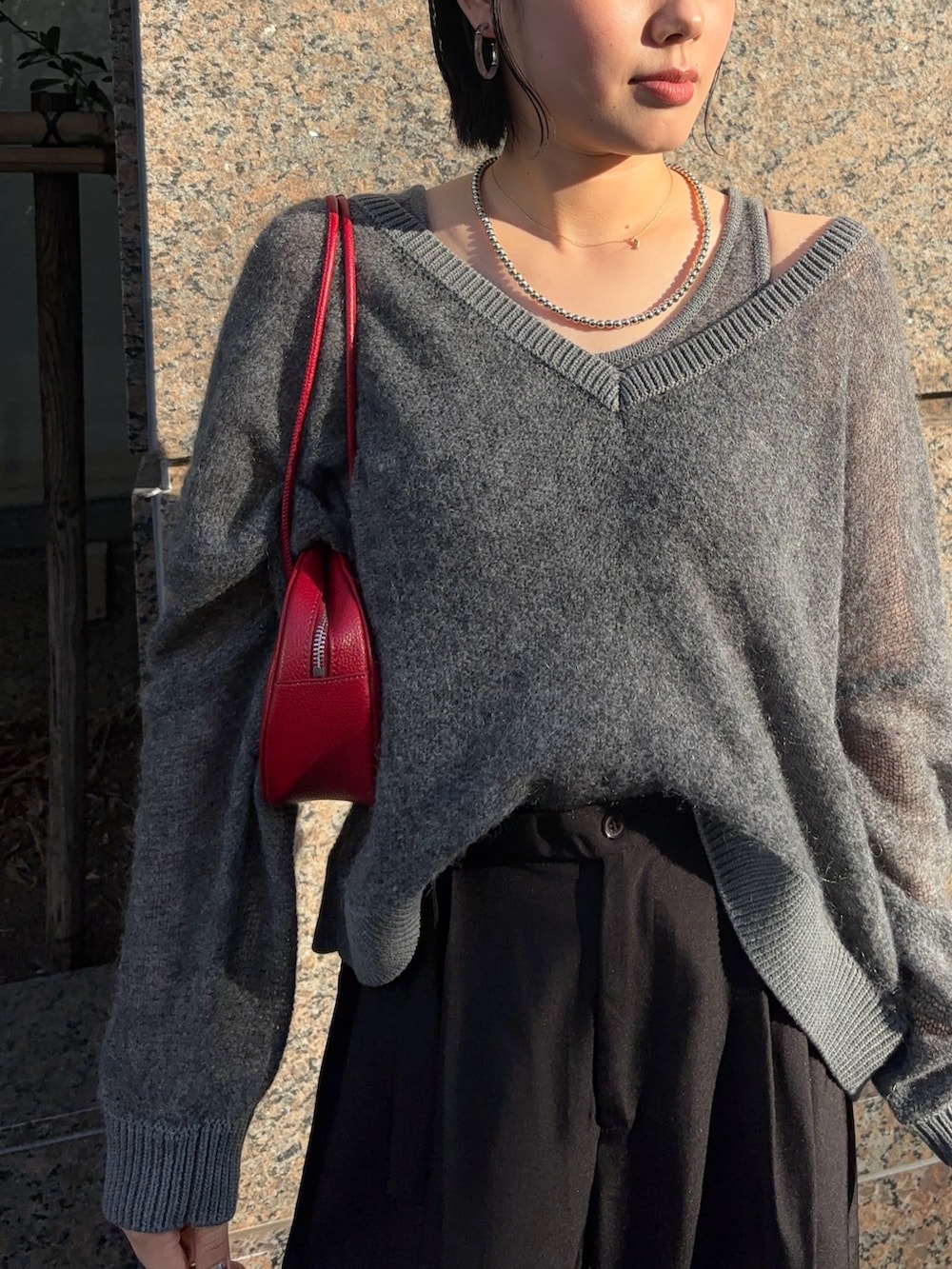 グレー系のニット/セーター、ブラック系のその他パンツ、ブラック系のブーツを着用したレディースの秋コーディネートの2枚目の写真