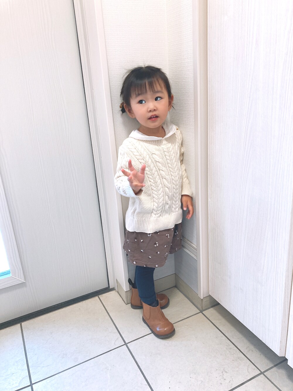 ブラウン系のパンツ、ブラウン系のブーツ、ホワイト系のニット/セーターを着用したキッズの冬コーディネートの2枚目の写真