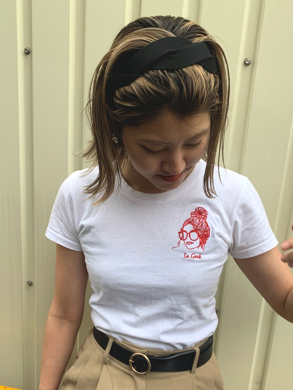 ベージュ系のスラックス、ブラック系のスニーカー、ブラック系のハンドバッグを着用したレディースの夏コーディネートの2枚目の写真