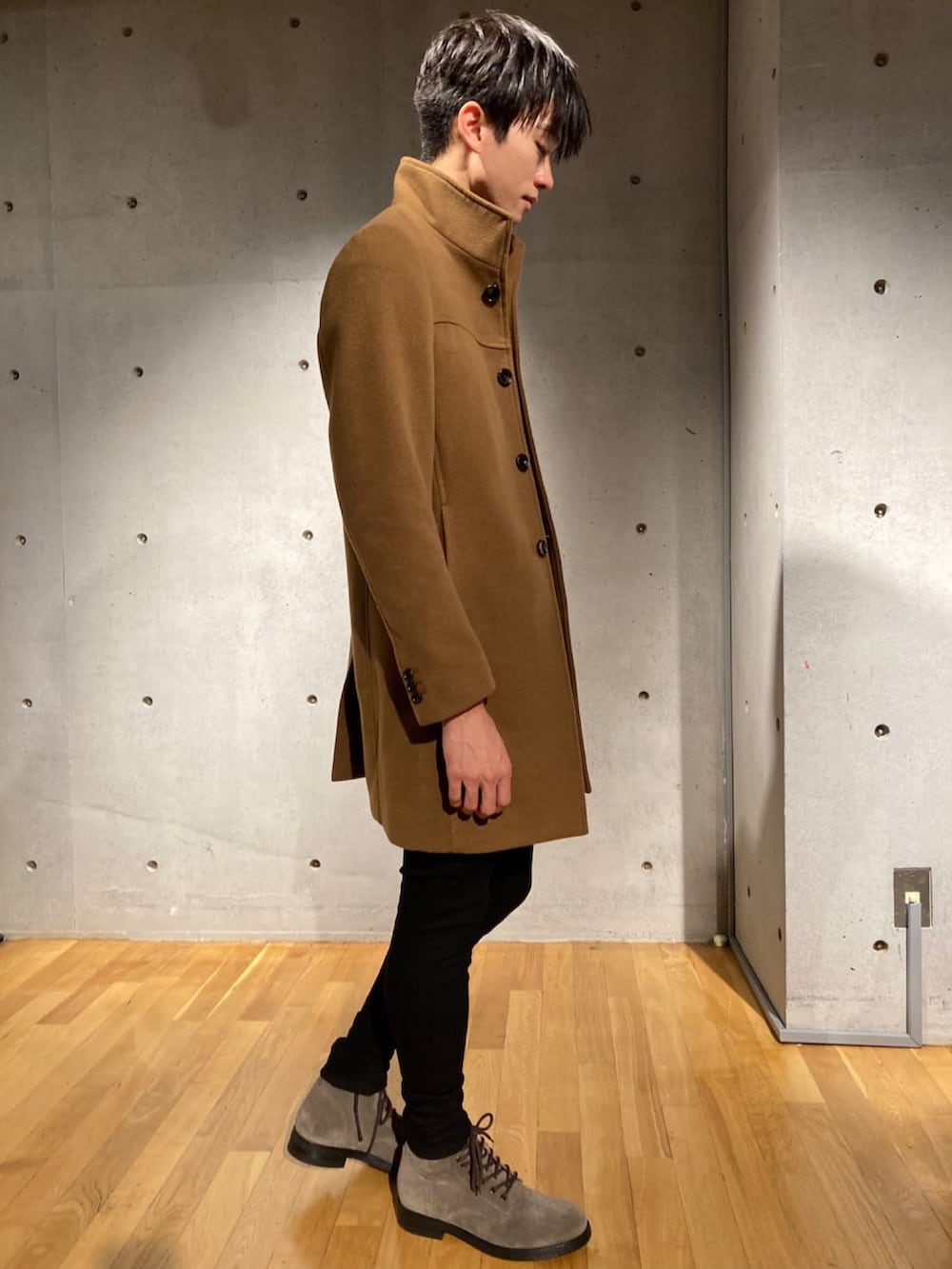 イエロー系のチェスターコート、グレー系のTシャツ/カットソー、ブラック系のカーゴパンツを着用したメンズの秋コーディネートの3枚目の写真