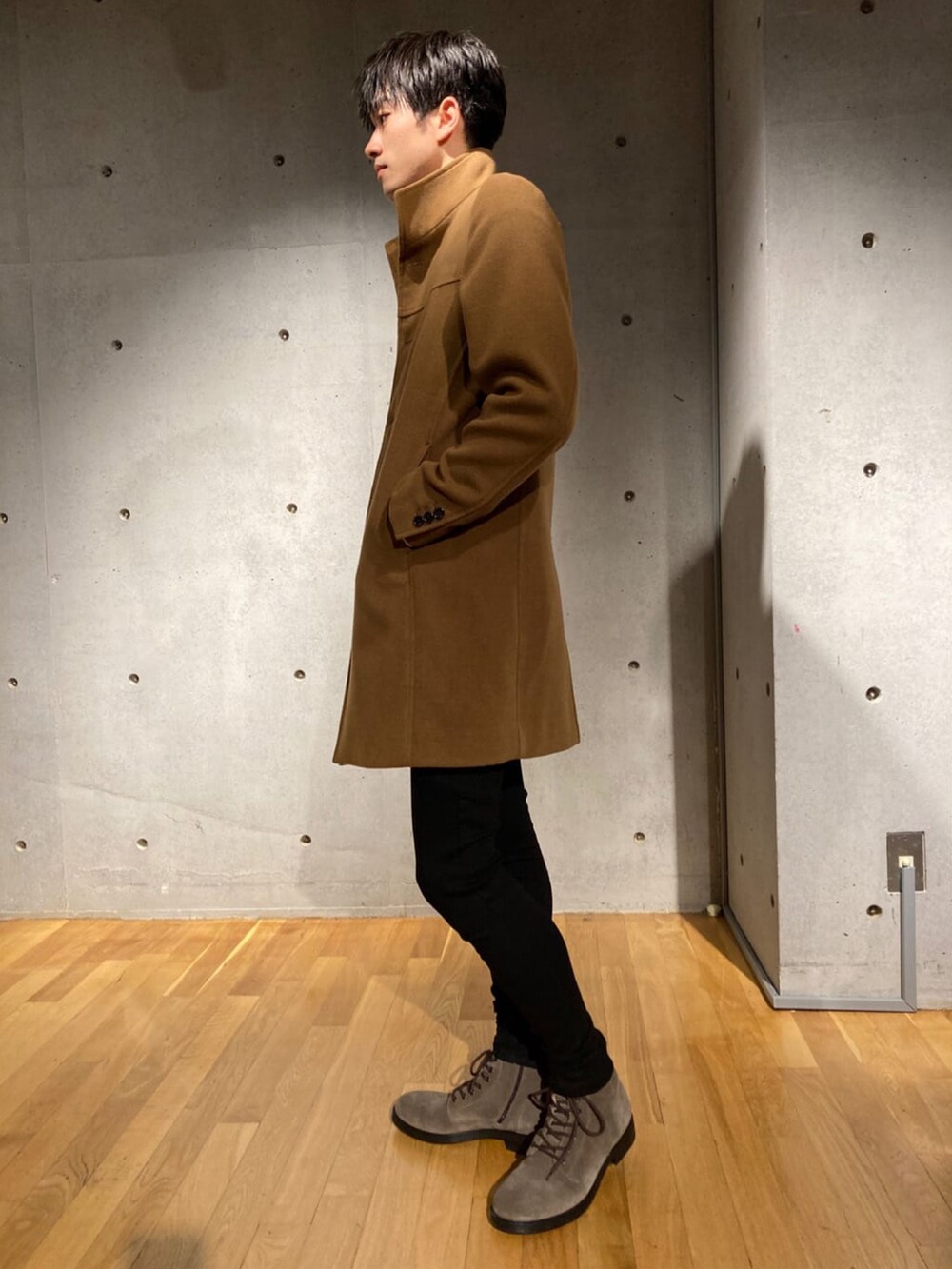 イエロー系のチェスターコート、グレー系のTシャツ/カットソー、ブラック系のカーゴパンツを着用したメンズの秋コーディネートの2枚目の写真