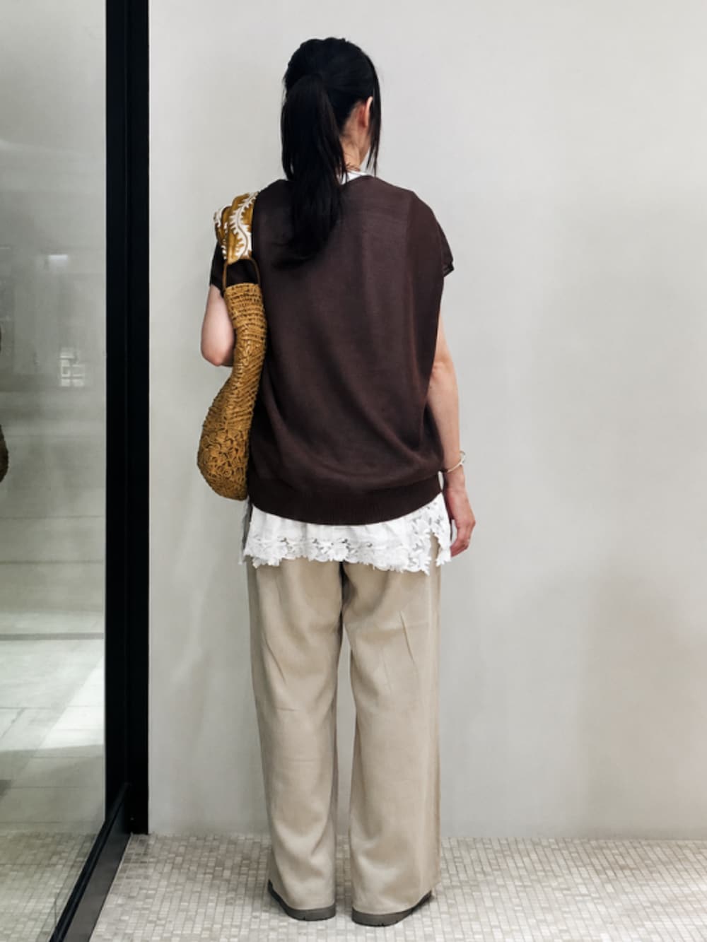 ブラウン系のトートバッグ、ブラウン系のニット/セーター、ホワイト系のTシャツ/カットソーを着用したレディースの夏コーディネートの2枚目の写真