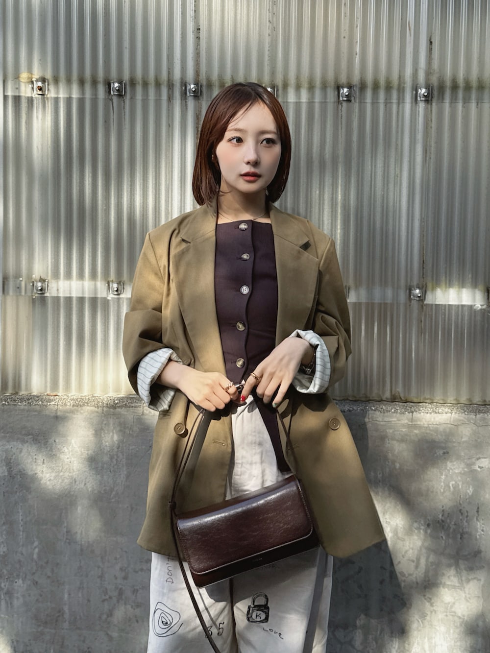 ブラウン系のベスト、グリーン系のテーラードジャケット、ホワイト系のその他パンツを着用したレディースの春コーディネートの2枚目の写真