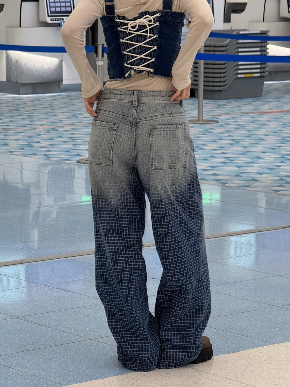 ブラウン系のブーツ、ブルー系のベスト、ブルー系のデニムパンツを着用したレディースの春コーディネートの3枚目の写真