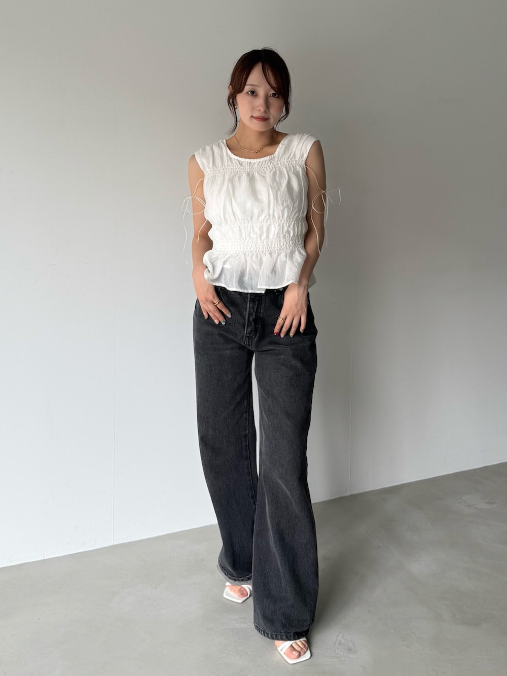 ブラック系のデニムパンツを着用したレディースの春コーディネートの2枚目の写真