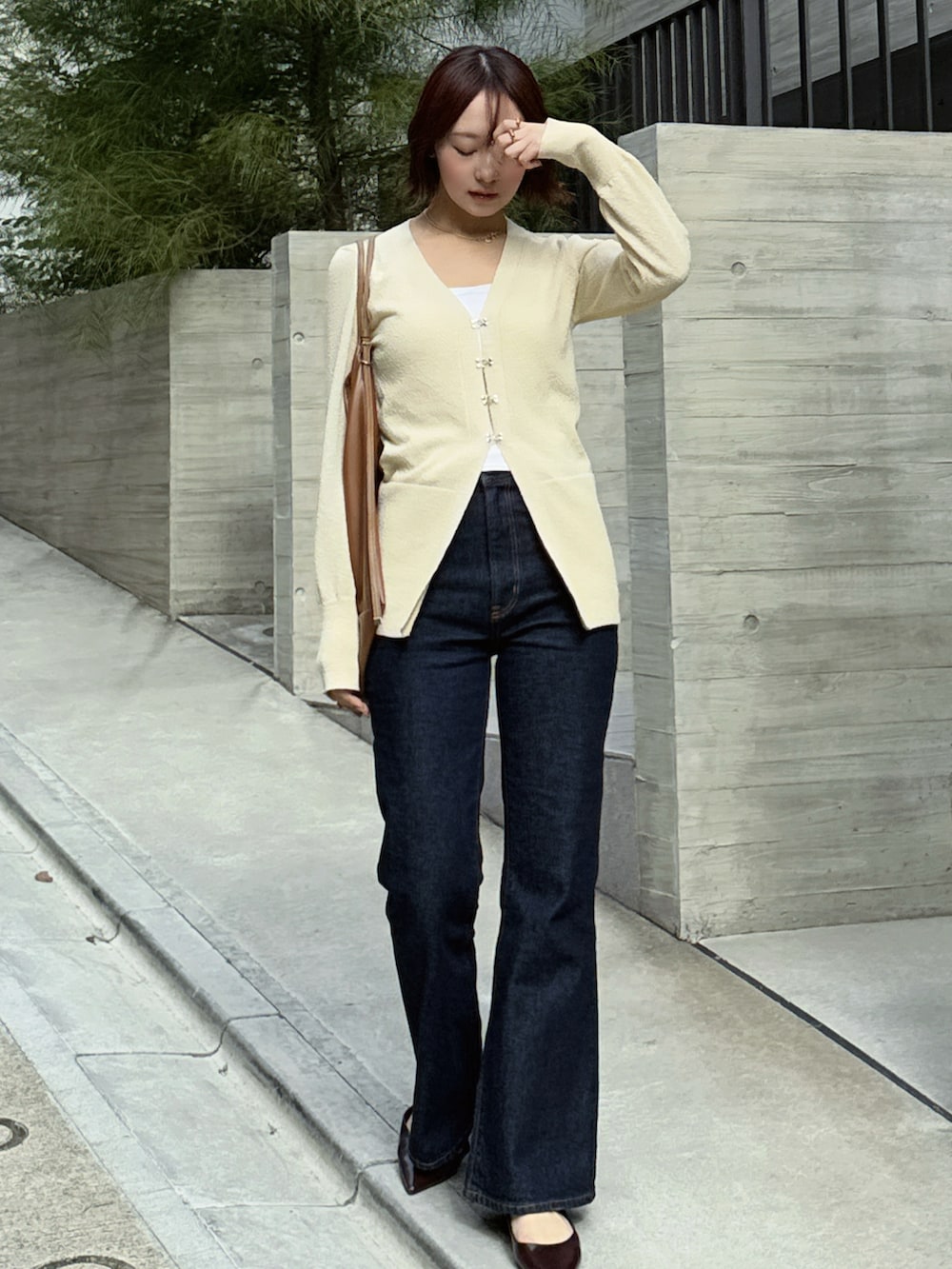 ブルー系のデニムパンツ、ブラウン系のショルダーバッグ、ブラウン系のパンプスを着用したレディースの冬コーディネートの3枚目の写真