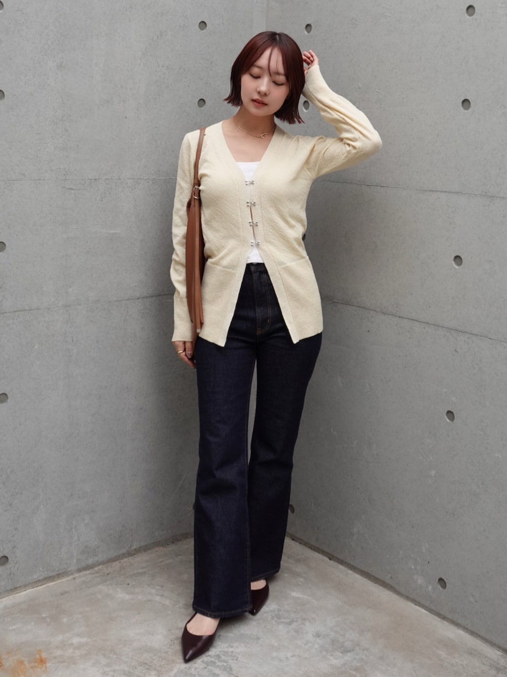 ブルー系のデニムパンツ、ブラウン系のショルダーバッグ、ブラウン系のパンプスを着用したレディースの冬コーディネートの2枚目の写真