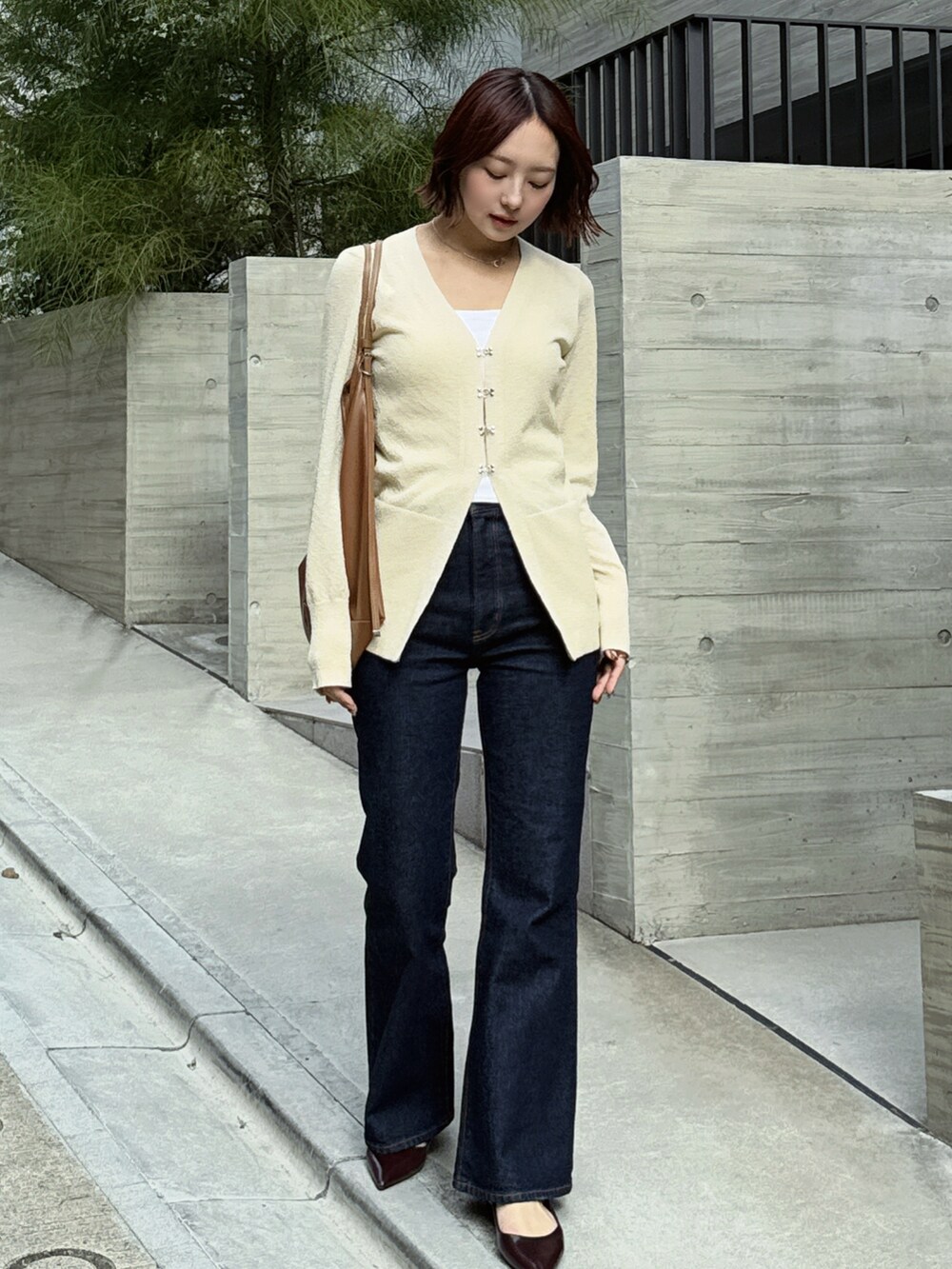 ブルー系のデニムパンツ、ブラウン系のショルダーバッグ、ブラウン系のパンプスを着用したレディースの冬コーディネートの4枚目の写真