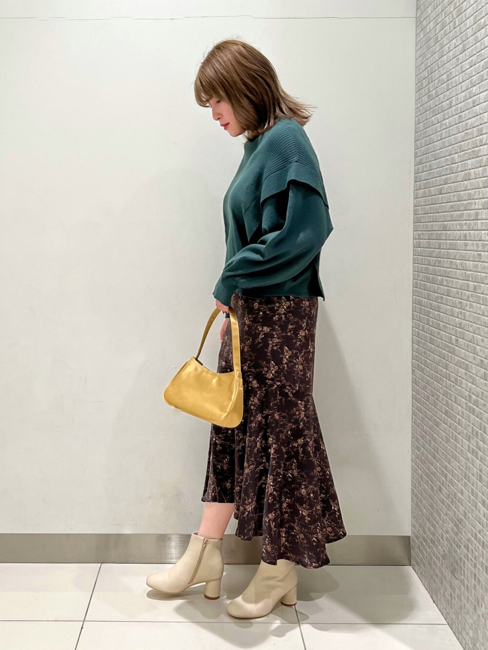 グリーン系のニット/セーター、ブラウン系のスカート、ホワイト系のブーツを着用したレディースの冬コーディネートの2枚目の写真