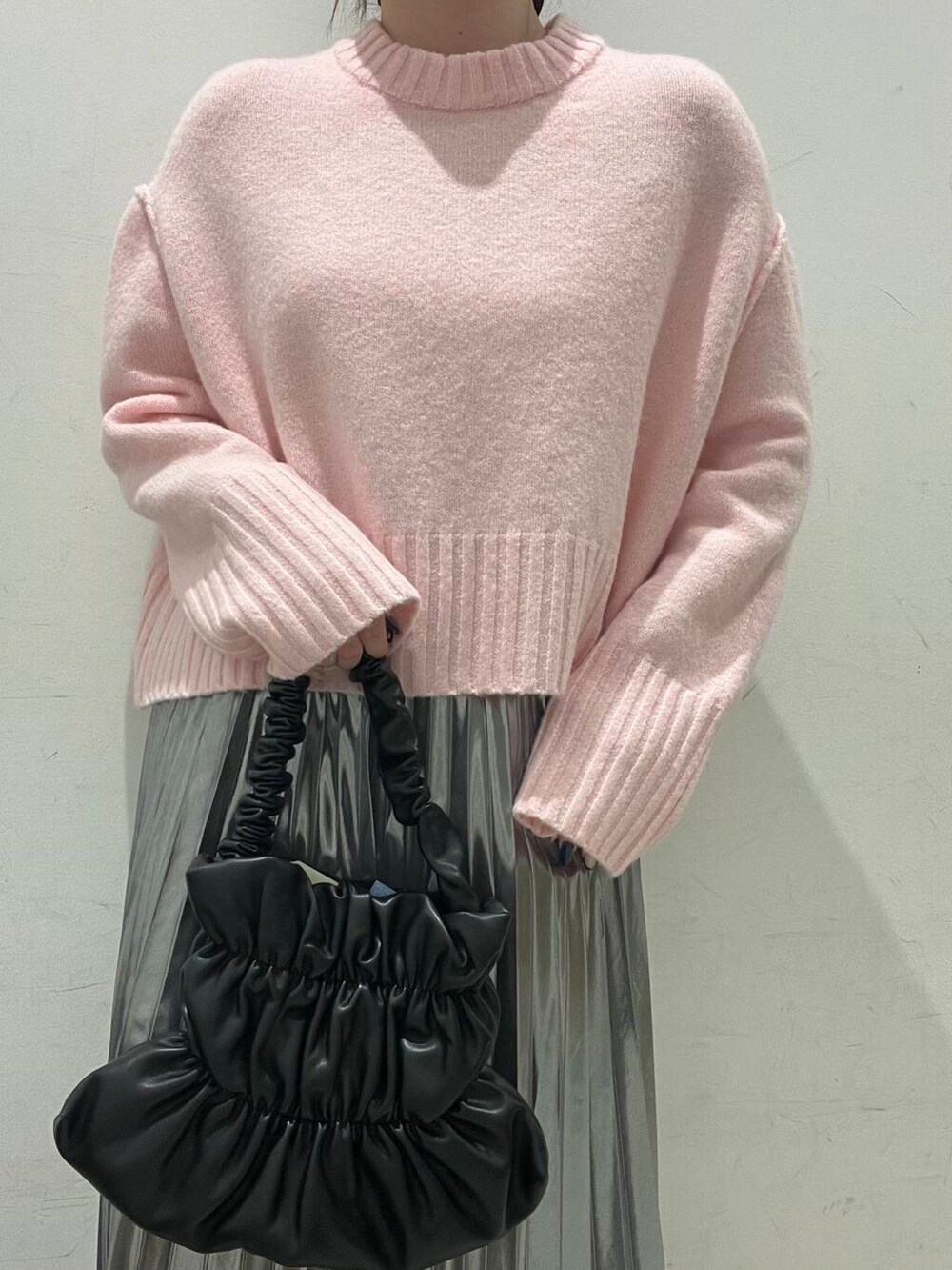 ブラック系のハンドバッグ、ブラック系のブーツ、シルバー系のスカートを着用したレディースの冬コーディネートの3枚目の写真