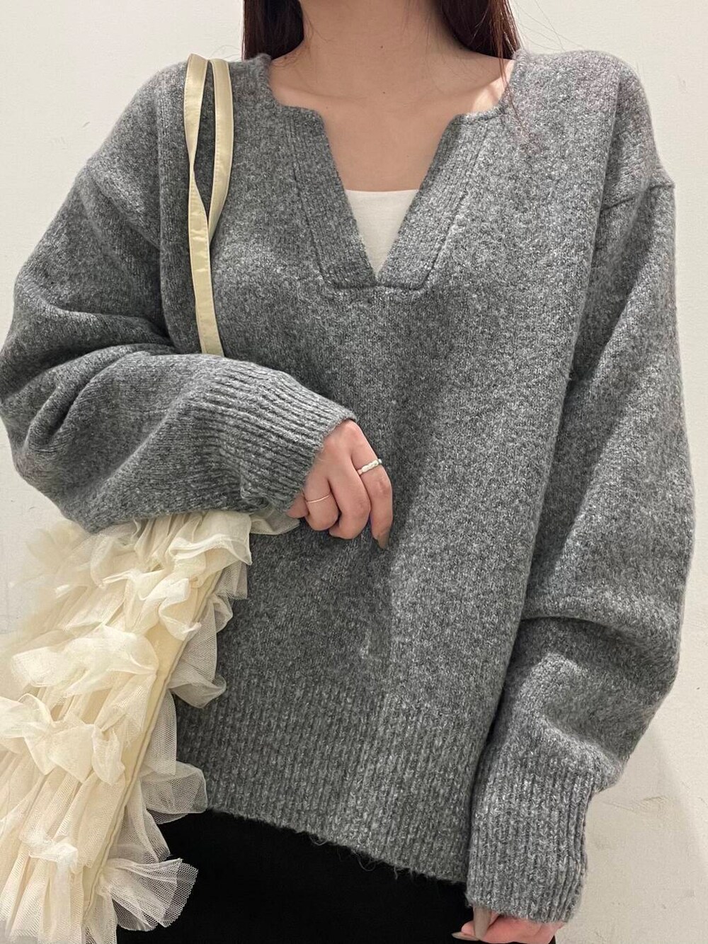 ホワイト系のトートバッグ、グレー系のスニーカー、グレー系のスカートを着用したレディースの冬コーディネートの3枚目の写真