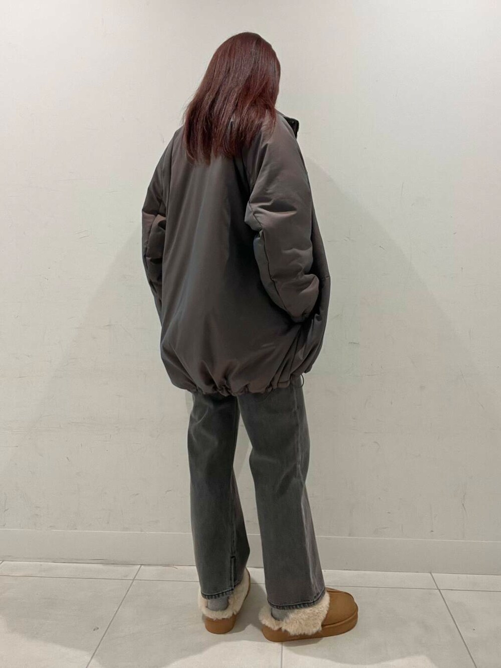 オレンジ系のハンドバッグ、ホワイト系のニット/セーター、ブラウン系のダウンジャケット/コートを着用したレディースの冬コーディネートの2枚目の写真