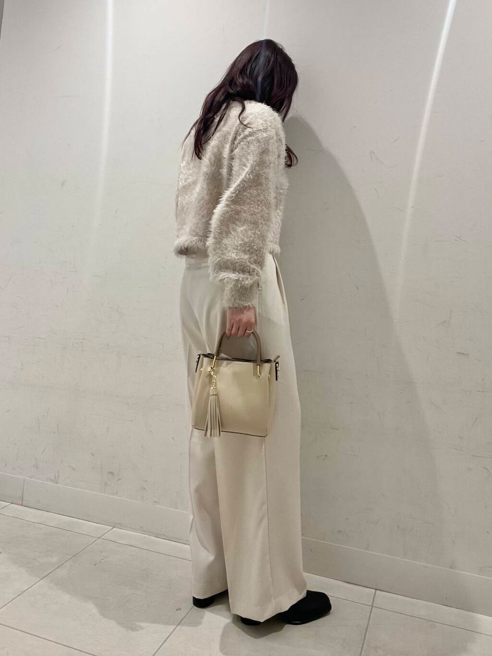 ホワイト系のトートバッグ、ブラック系のブーツ、ベージュ系のニット/セーターを着用したレディースの冬コーディネートの2枚目の写真