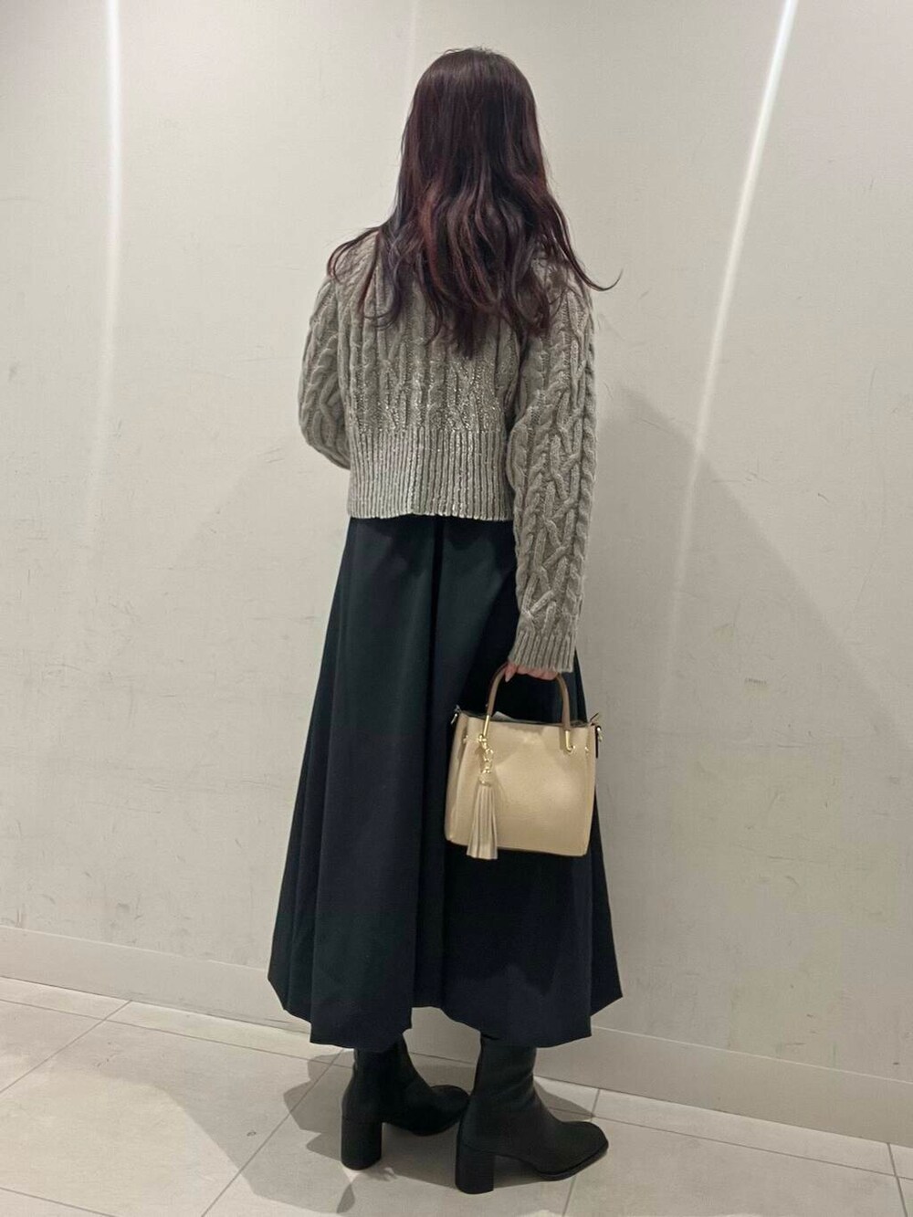 ホワイト系のトートバッグ、ブルー系のスカート、ブラック系のブーツを着用したレディースの冬コーディネートの2枚目の写真