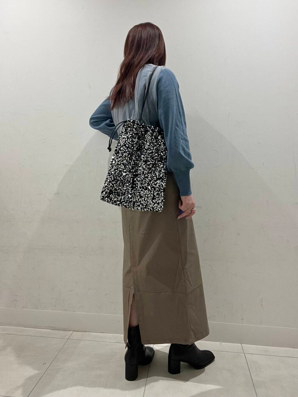 ブラウン系のスカート、ブラック系のブーツ、シルバー系のトートバッグを着用したレディースの冬コーディネートの2枚目の写真